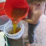 Money lessons for kids shown through Flynn pouring honey for his business