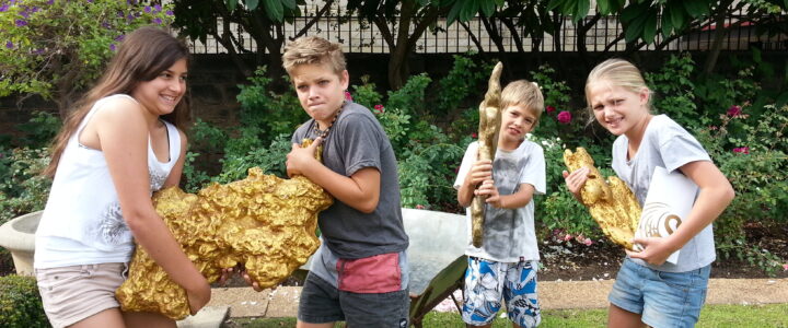 Kids holding large display gold nuggets outside the Perth Mint while learning about buying Perth Mint coins
