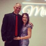 Cathy and Trevor at a network marketing event standing under a millionaire sign